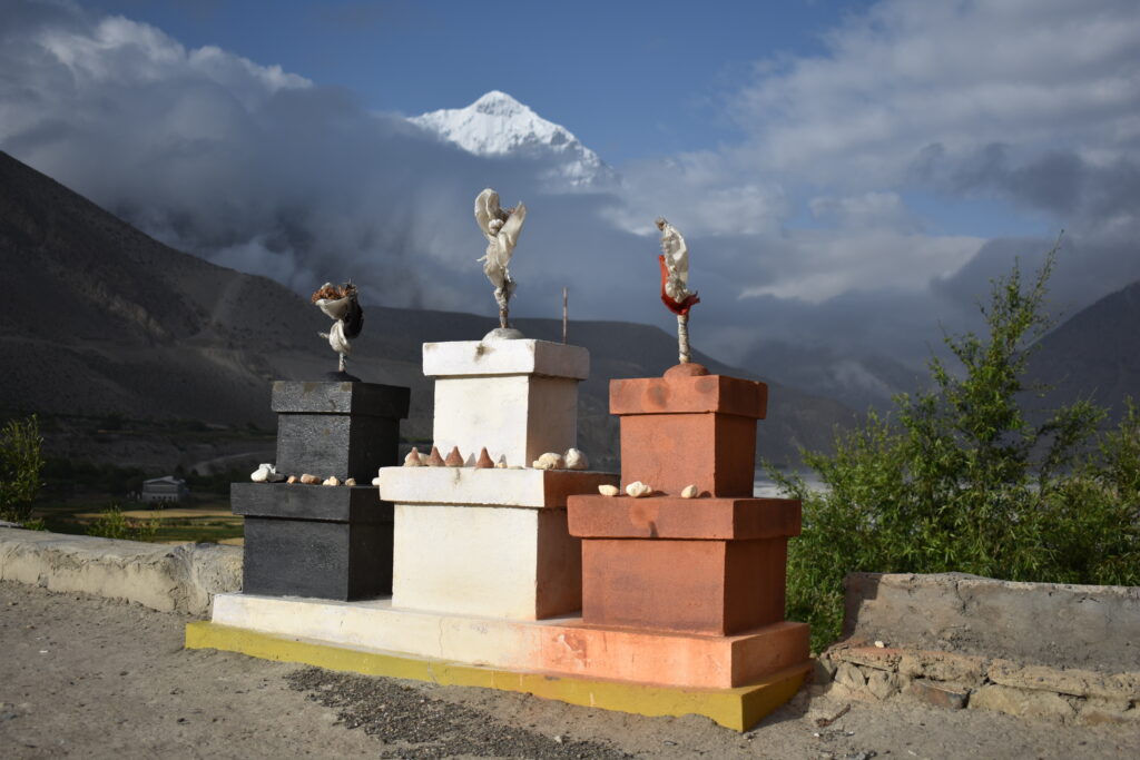 image of three chörten on a roof with Nilgiri in the background