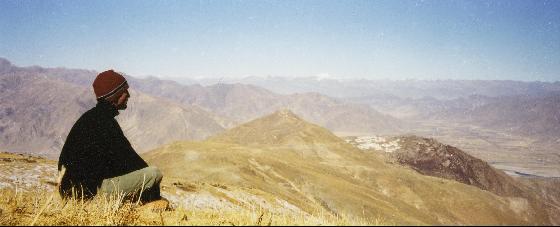 Person sitting on a mountaintop staring out into the distance