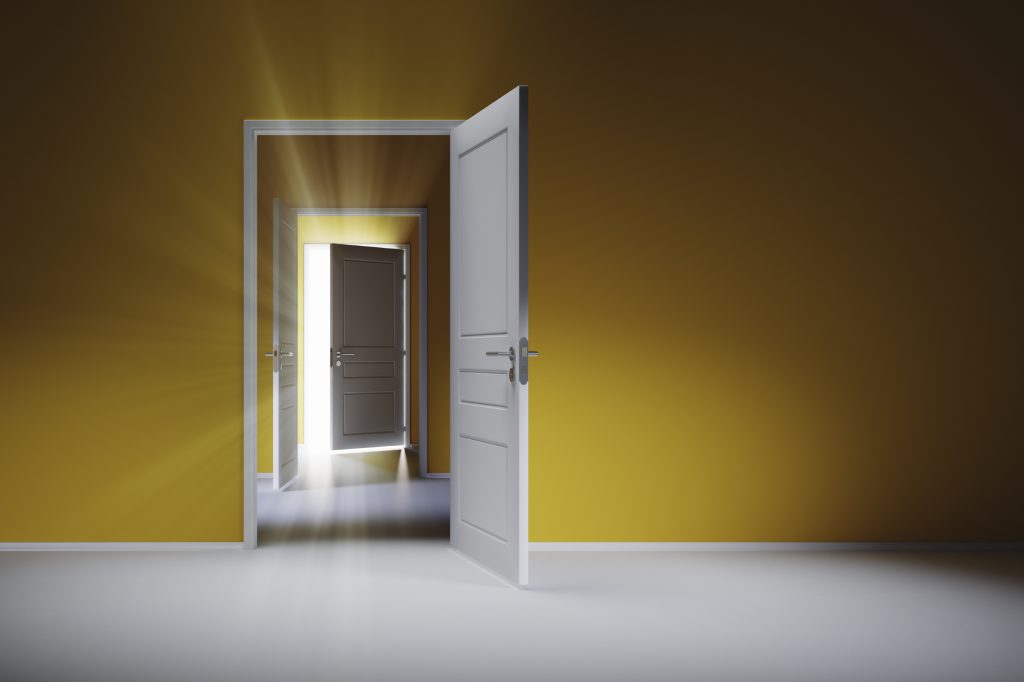 Three open white doors on the yellow wall. Rays of light shine through the open door.