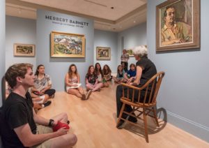 Students of the Museum anthropology class sit on the floor of the Fleming's Wolcott Gallery while listening to a guest lecturer.