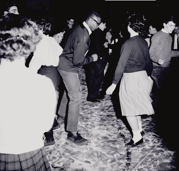 Photograph of a male and female student dancing a crowd of other students. 