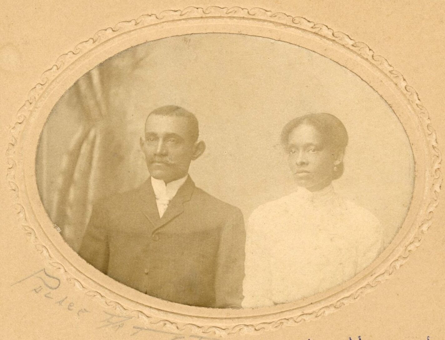 Studio photograph of a Black man and woman in front of a studio backdrop.