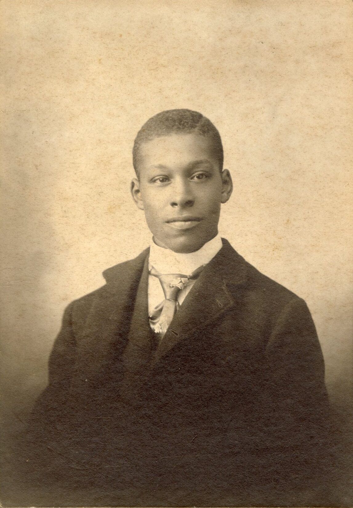 Studio portrait of a young black man wearing a suit and fancy tie.