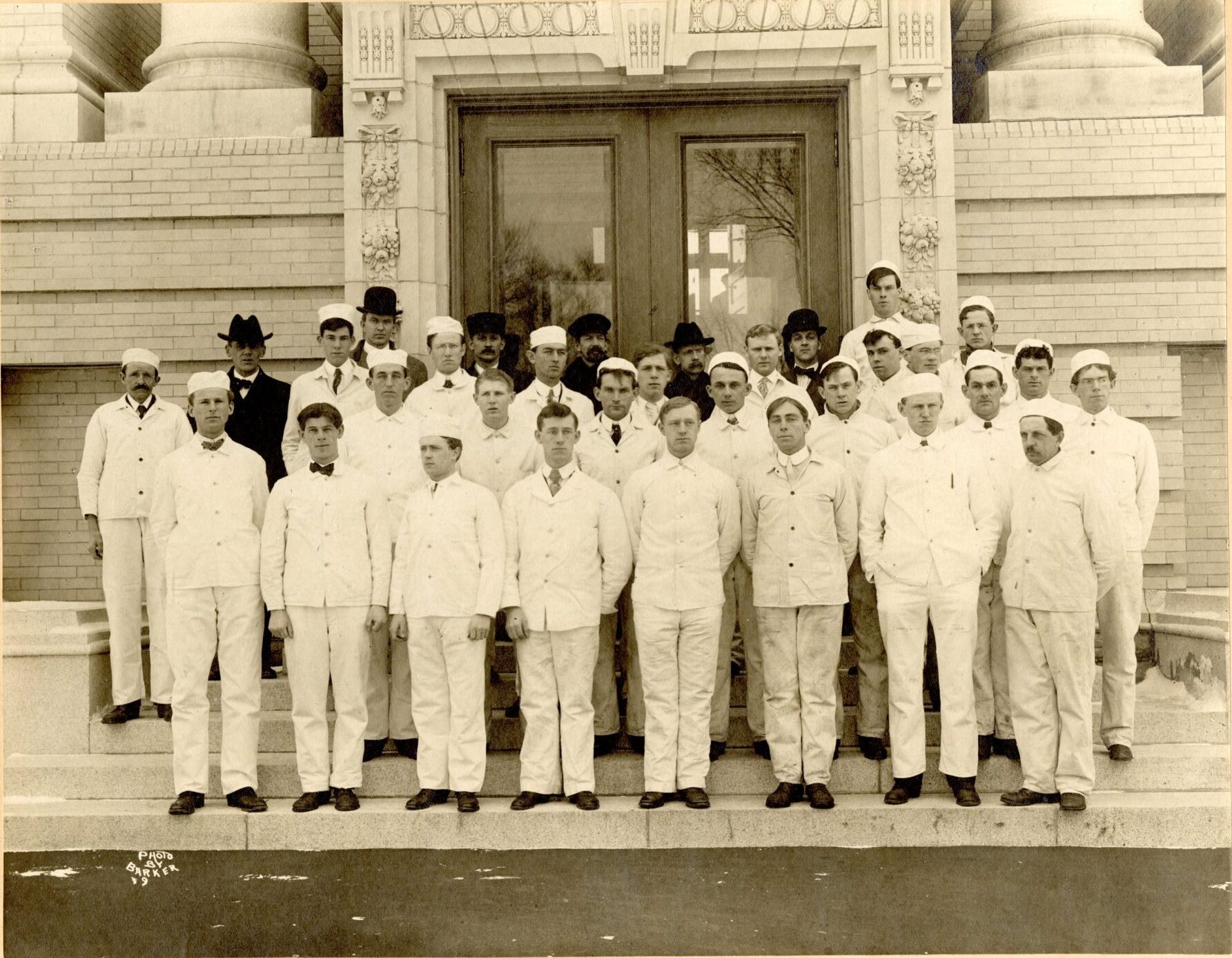 Dairy school students in white uniforms stand in front of the Morrill Hall main entrance.