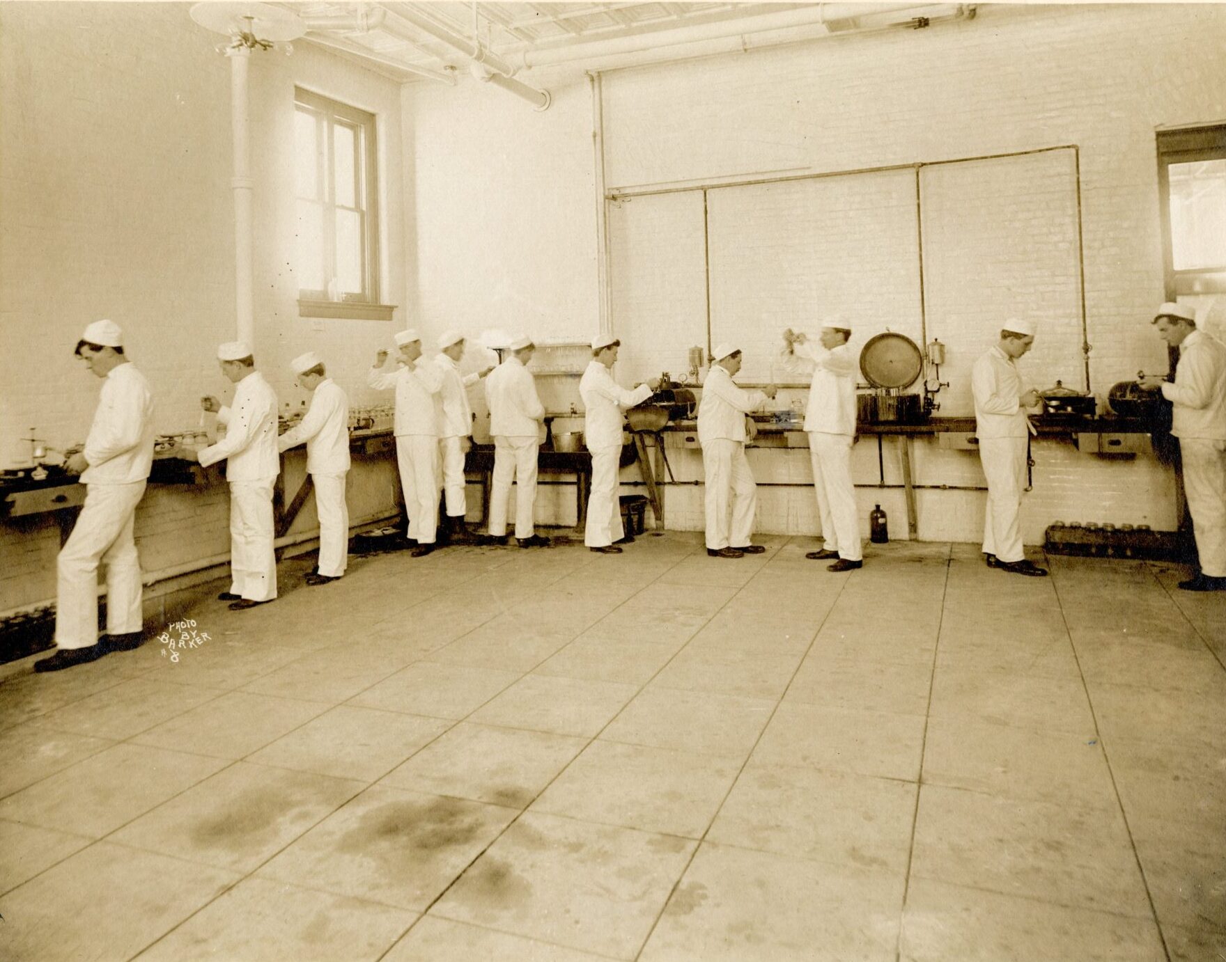 Dairy School students in white uniforms working with buttermaking equipment in a laboratory.