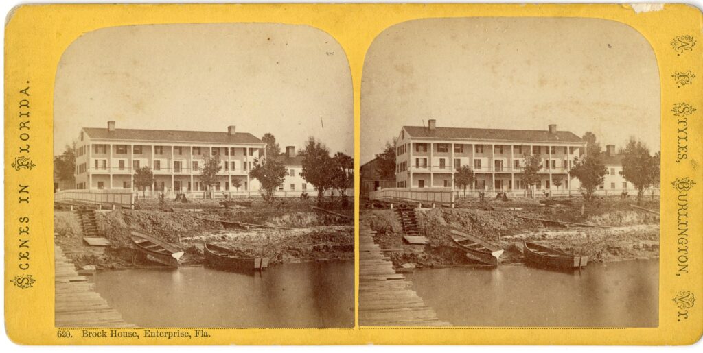 Two photographs mounted side by side on a yellow card showing a l3-story white hotel on a shoreline with small boats in the water.