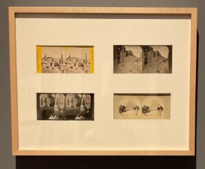 Four stereographs mounted in a wooden frame hanging on a wall.