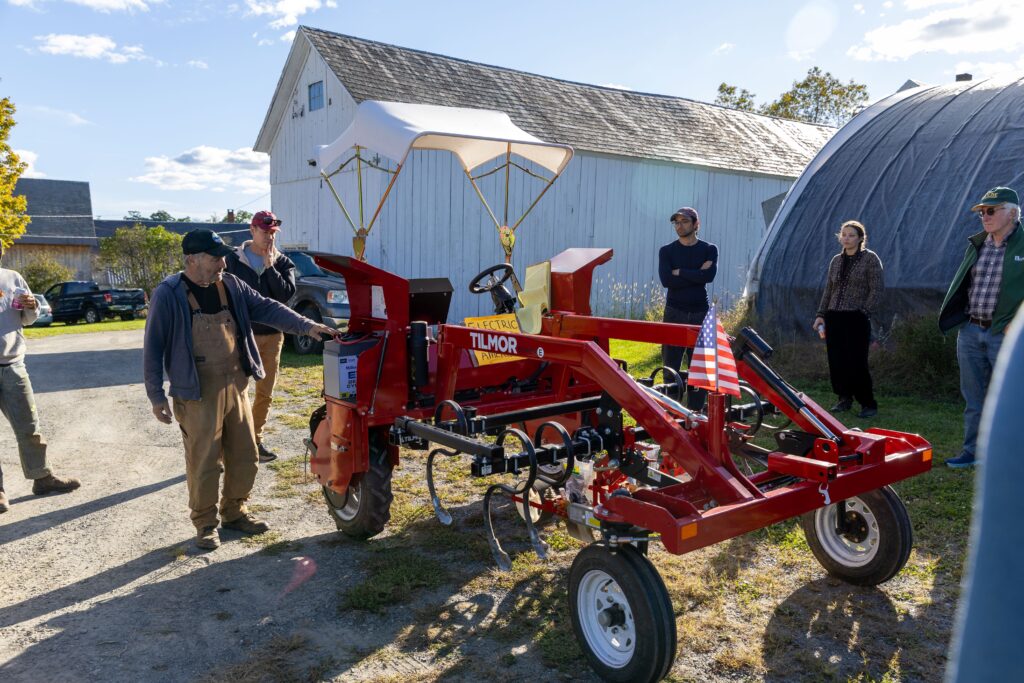 Group of farmer gathered around Tilmor electric tractor