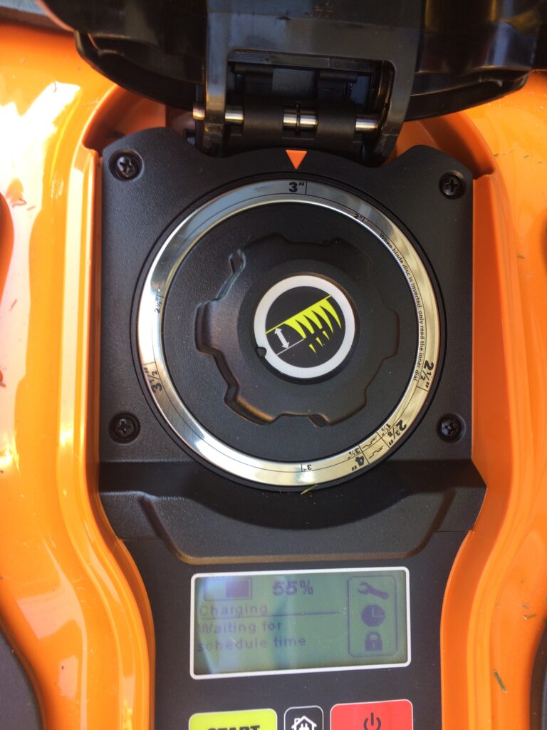 Photo of the inside of a robotic mower where the length of grass height to cut to is set by a dial.