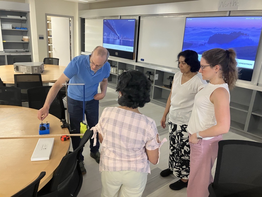 UVM instructors discuss a spring oscillation demo in the physics active learning classroom