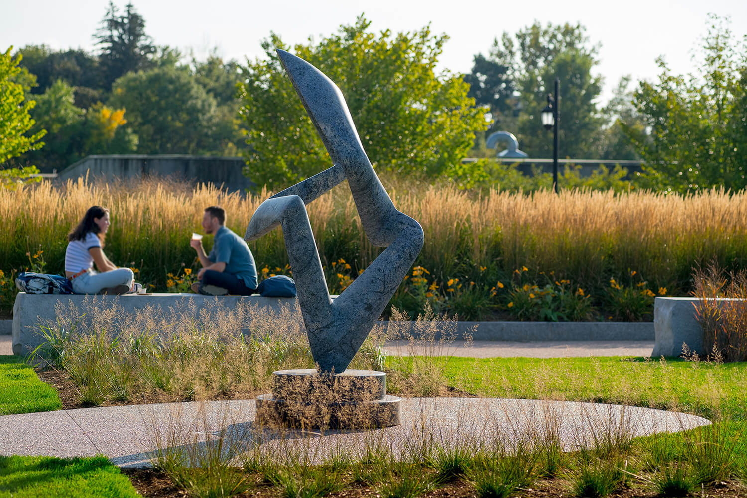 Students sitting near a sculpture by the sculpture entitled "Arete Blu" by Richard Erdman